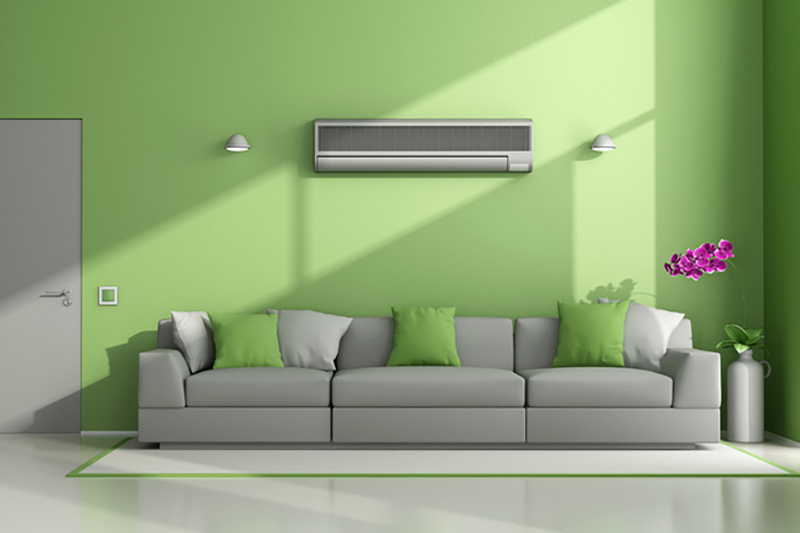 Blog Title: What Is a Ductless AC? Photo: Ducless AC unit wall mounted in green and grey living room