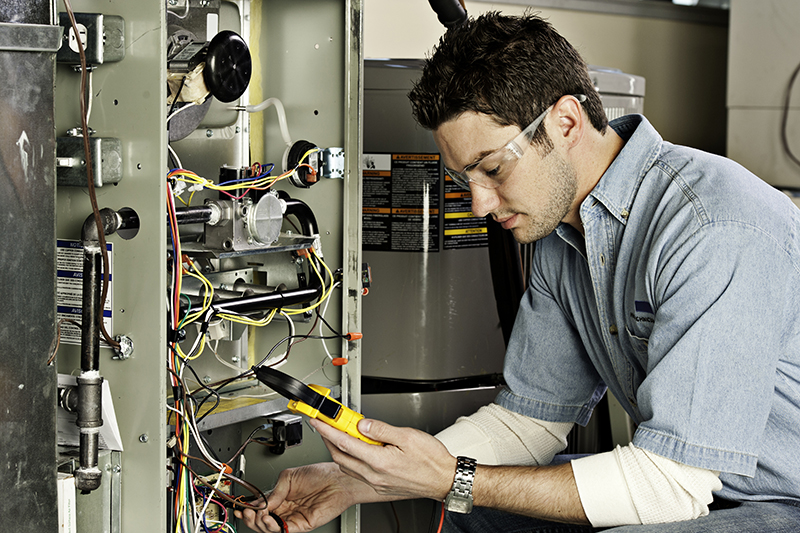 Service technician testing a furnace. 5 Reasons to Schedule a Fall Furnace Clean and Check.