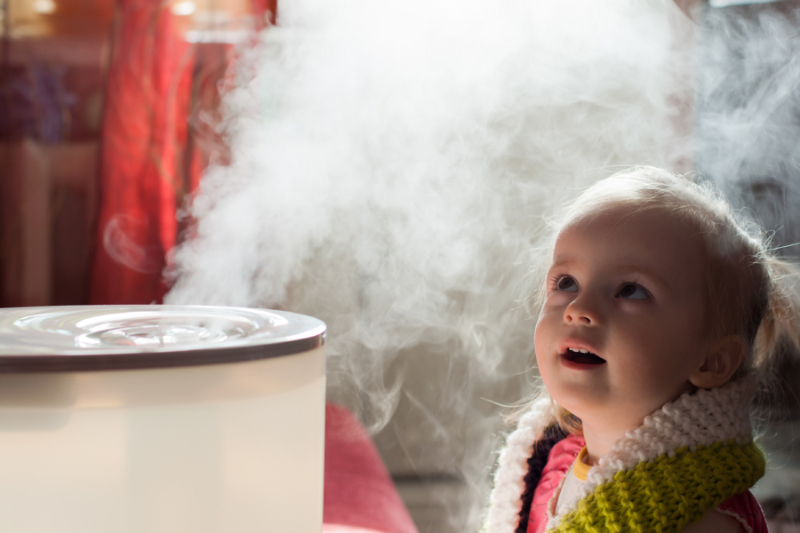 Benefits of Using a Humidifier in Your Home. Little baby playing with humidifier.